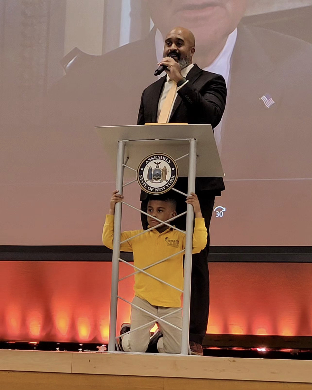 Marlon speaking at an event while his son watches the audience through the pulpit